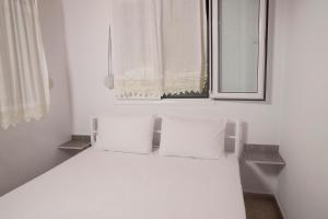 a white bed with two pillows sitting under a window at Dimitra House in Metamorfosi