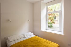 a bedroom with a yellow blanket and a window at Artist's Studio in Stockbridge in Edinburgh