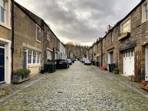 a cobblestone street with cars parked on the sides of buildings at Artist's Studio in Stockbridge in Edinburgh