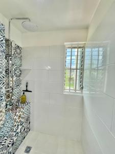 bagno bianco con doccia e finestra di Appartement Frida de la Marina a Les Trois-Îlets