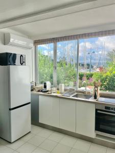 una cucina con elettrodomestici bianchi e una grande finestra di Appartement Frida de la Marina a Les Trois-Îlets