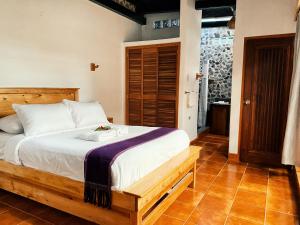 1 dormitorio con 1 cama con marco de madera en El Dragon Hotel, en San Marcos La Laguna