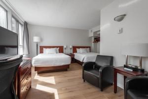 a hotel room with two beds and a flat screen tv at Hotel les Suites Labelle in Montreal