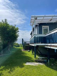 una casa azul con un porche en un campo de césped en Charming coastal house with an ocean view, en Garten