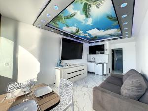a living room with a couch and a table and a tv at 240 Magnifique Appart Deluxe Hammam vue mer in Cap d'Agde