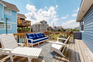 a deck with two chairs and a blue couch at Cap'n Stilts in Hatteras