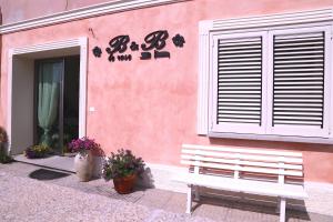 een witte bank buiten een roze gebouw bij B&B Le Rose in Olbia