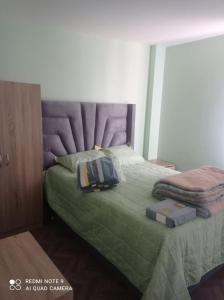 a bedroom with a green bed with a purple headboard at DEPARTAMENTO EN YANAHUARA 3er piso in Arequipa