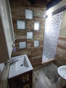 baño con lavabo y ducha con paredes de madera. en Cabañas Epuyen en Trevelín
