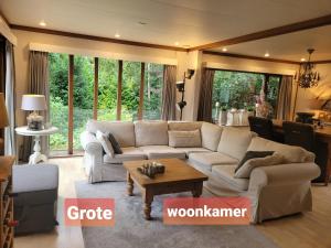 een woonkamer met een bank en een tafel bij De Blauwe Reiger mooi dubbel chalet in de Veluwse bossen in Putten