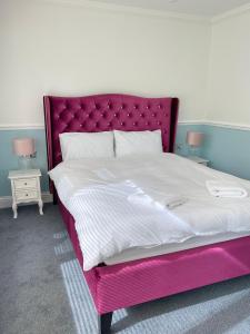 a bed with a pink bed frame and two tables at Arrandale Lodge in Norwich