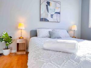 1 dormitorio con 1 cama blanca con 2 lámparas y una planta en Fully furnished Townhome with Driveway Near DT, en Ottawa