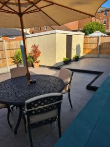 - une table et des chaises noires avec un parasol sur la terrasse dans l'établissement North Parade Holiday Apartment 35 Sea View Road Skegness PE25 1BS, à Skegness