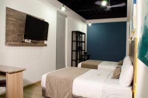 a bedroom with two beds and a tv on the wall at Hotel StayHome in Ensenada