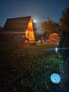 una carpa pirámide iluminada en un campo por la noche en A frame Sima, en Breb