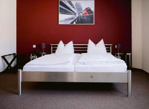 Bett mit weißer Bettwäsche und Kissen in einem Zimmer in der Unterkunft Hotel Landgasthof Zur Alten Scheune in Zweibrücken