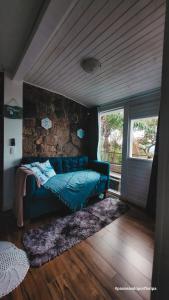 um quarto com um sofá azul e uma parede de pedra em Loft Com Lago Hidro e Vista Para o Mar em Florianópolis