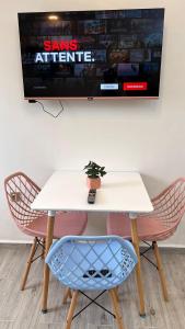 阿爾及爾的住宿－GOLF LOFT( BLUE S 78 )，一张白色的桌子和椅子,墙上配有电视
