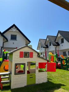 a play house in the grass in front of houses at Domki Słoneczka in Sarbinowo