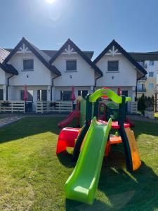 a playground with a slide in the grass at Domki Słoneczka in Sarbinowo