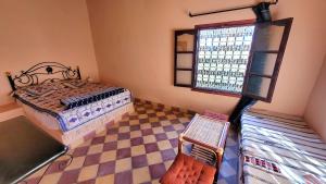 a bedroom with a bed and a checkered floor at Auberge Famille Benmoro in Skoura