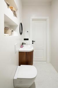 a white bathroom with a toilet and a sink at Tina's Riga apartments in Rīga