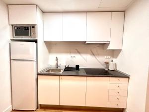 eine weiße Küche mit einer Spüle und einem Kühlschrank in der Unterkunft ANGELILLO DREAMS in Madrid