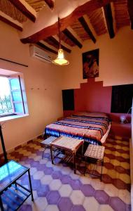 a room with a bed and two chairs and a table at Auberge Famille Benmoro in Skoura