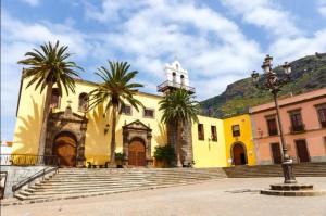 un edificio giallo con palme di fronte di La Casita de Daise a Garachico