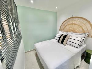 a bedroom with a white bed with pillows on it at Appartement Belbo de la Marina in Les Trois-Îlets