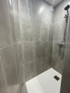 ein Bad mit einer Dusche und einer Fliesenwand in der Unterkunft Sydel2 in Paris