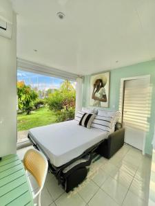 a bedroom with a large bed and a window at Appartement Belbo de la Marina in Les Trois-Îlets