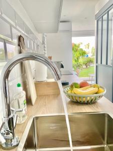 a kitchen sink with a faucet and a bowl of fruit at Appartement Belbo de la Marina in Les Trois-Îlets