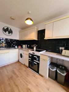 a kitchen with white cabinets and a washer and dryer at VALE VIEW APARTMENT, Prestatyn, North Wales - a smart and stylish, dog-friendly holiday let just a 5 min walk to beach & town! in Prestatyn
