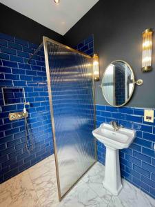 een blauwe badkamer met een douche en een wastafel bij The Bedford Inn in Kent