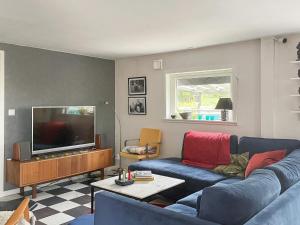 Il comprend un salon doté d'un canapé bleu et d'une télévision à écran plat. dans l'établissement Holiday home ORMARYD II, à Ormaryd