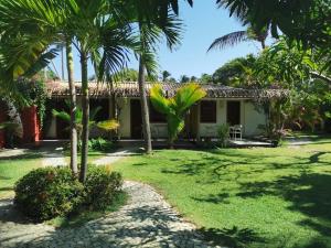 a house with palm trees in front of a yard at Le Jardin d'Éole - Pousada em Pontal de Maceio in Fortim