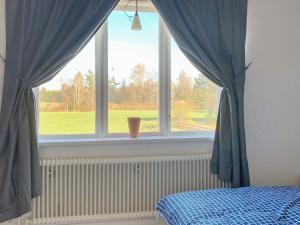 Holiday home VETLANDA في فيتلاندا: غرفة نوم مع نافذة مع ستائر زرقاء وسرير