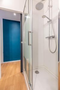een glazen douche in een badkamer met een blauwe deur bij Astridôme in Châtel-Guyon
