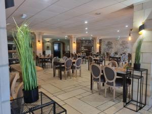 ein Restaurant mit Tischen, Stühlen und Pflanzen in der Unterkunft Hôtel Le Prieuré in Rancourt