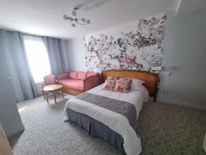 ein Schlafzimmer mit einem Bett und einem rosa Stuhl in der Unterkunft Hôtel Le Prieuré in Rancourt