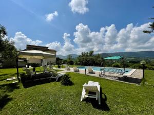 a yard with a pool with chairs and an umbrella at Villa con Piscina Donna Romina in SantʼAgata deʼ Goti
