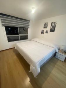 un letto bianco in una stanza con finestra di Apartamento en castropol a Medellín