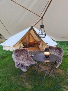 une tente avec deux chaises et une table en face de celle-ci dans l'établissement Au Pied Du Trieu, the glamping experience, à Labroye