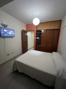 a bedroom with a white bed and a flat screen tv at Departamento frente a la CASA HISTÓRICA DE TUCUMAN in San Miguel de Tucumán