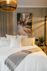 a bedroom with a white bed with a painting on the wall at Leopard's Khaya, Marloth Park in Marloth Park