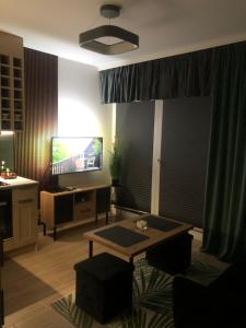 a living room with a table and a television at Apartament Patio Vita -garaż podziemny, taras,wejście klamka kod,centrum in Kielce