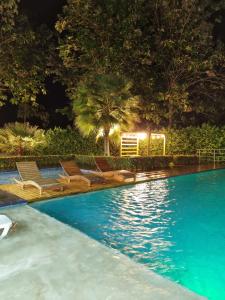 una piscina por la noche con sillas y árboles en Hotel Puerto Triunfo en Doradal