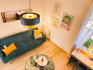 een woonkamer met een groene bank en een tafel bij La Noé d'Or by Madame Conciergerie in Bruz