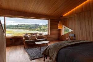 a bedroom with a bed and a couch and a large window at Tierra Chiloe in San José